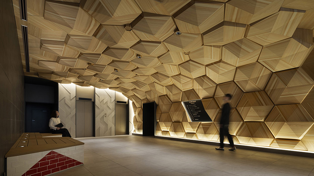 A person sitting on a bench in a large room with a person standing.