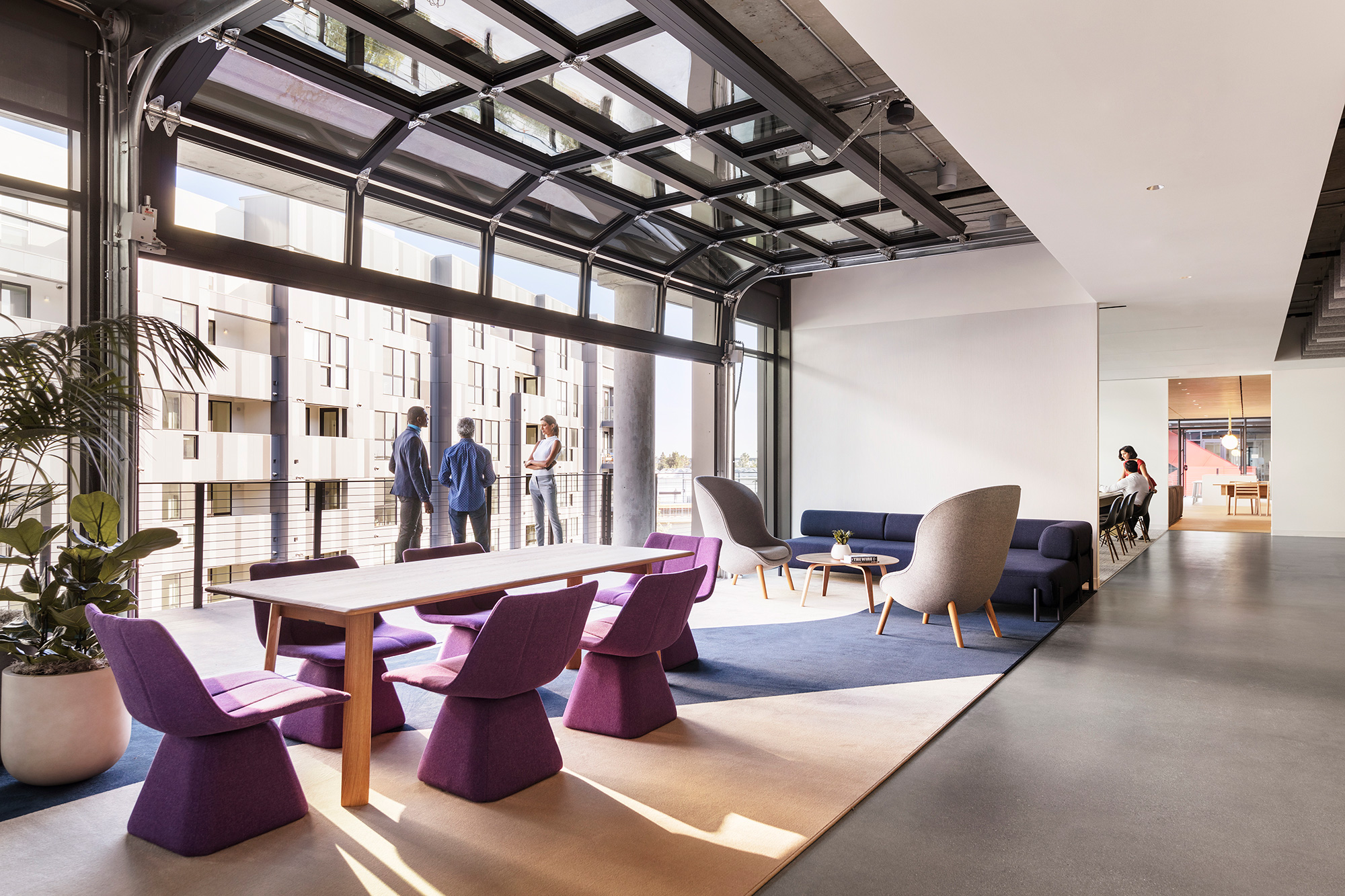 A room with a table chairs and a plant in it.