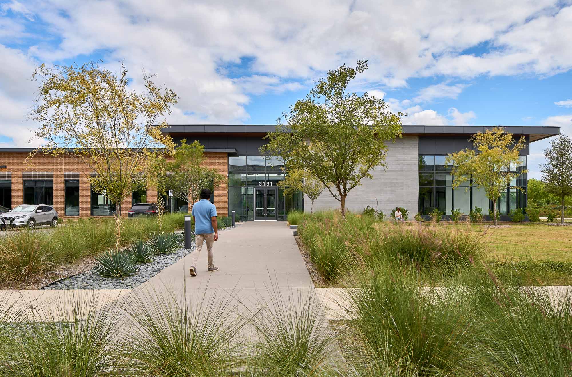 A person walking on a dirt path in front of a building.