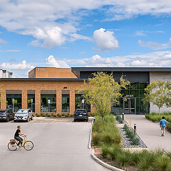 A person riding a bicycle on a street in front of a building.