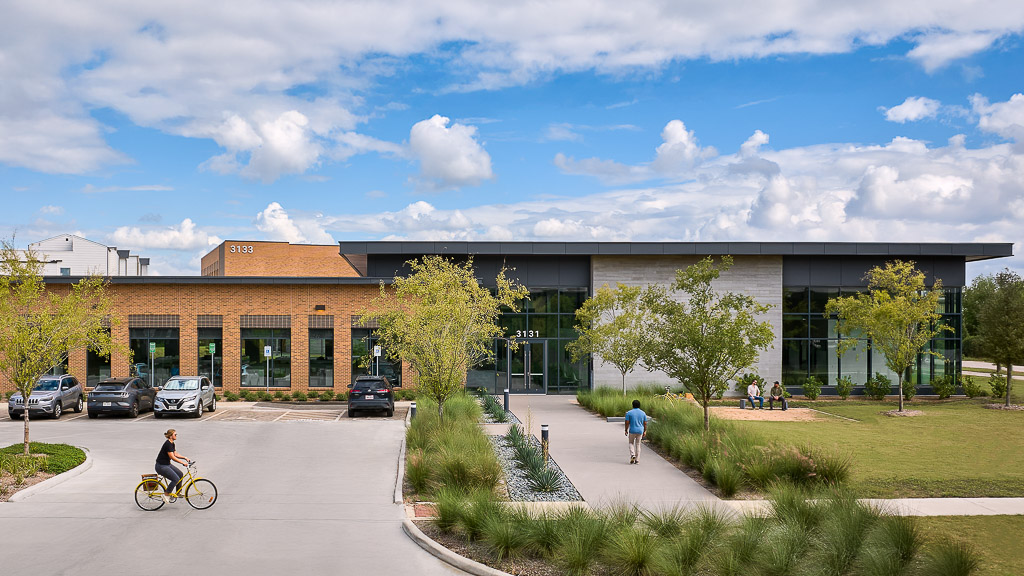 A building with a parking lot and cars in front.