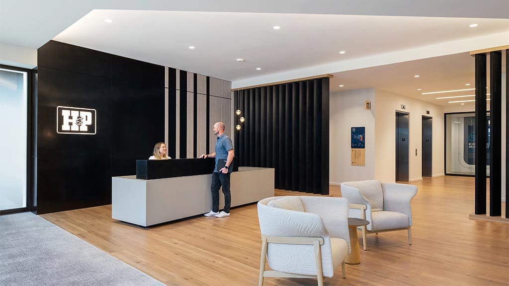 A man and a woman in a room with a black wall and chairs.