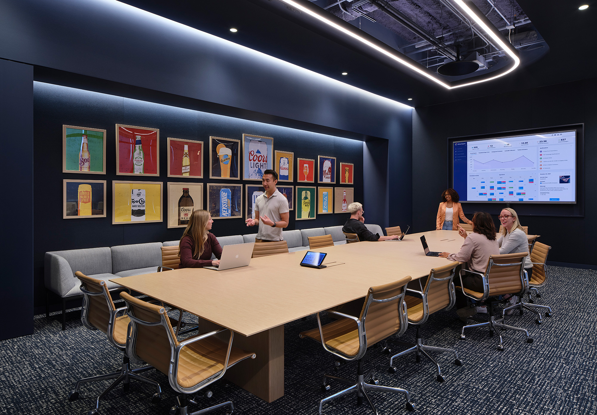 A group of people sitting around a table with a projector screen.