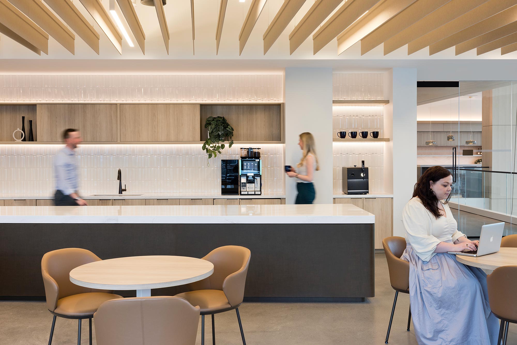 A woman standing in front of a man and a woman sitting at a table.