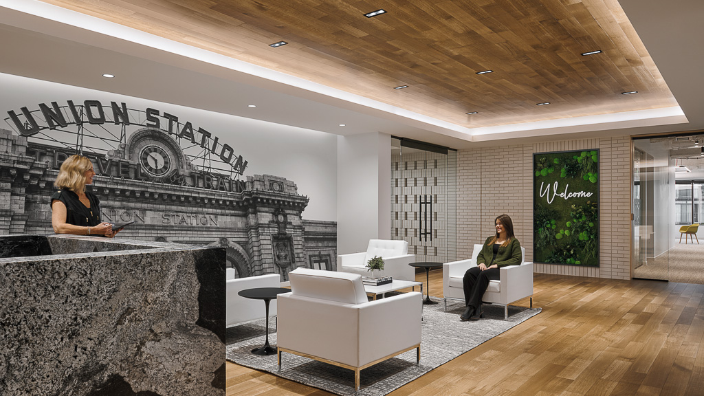A couple of women sitting in a room with a large rock wall.