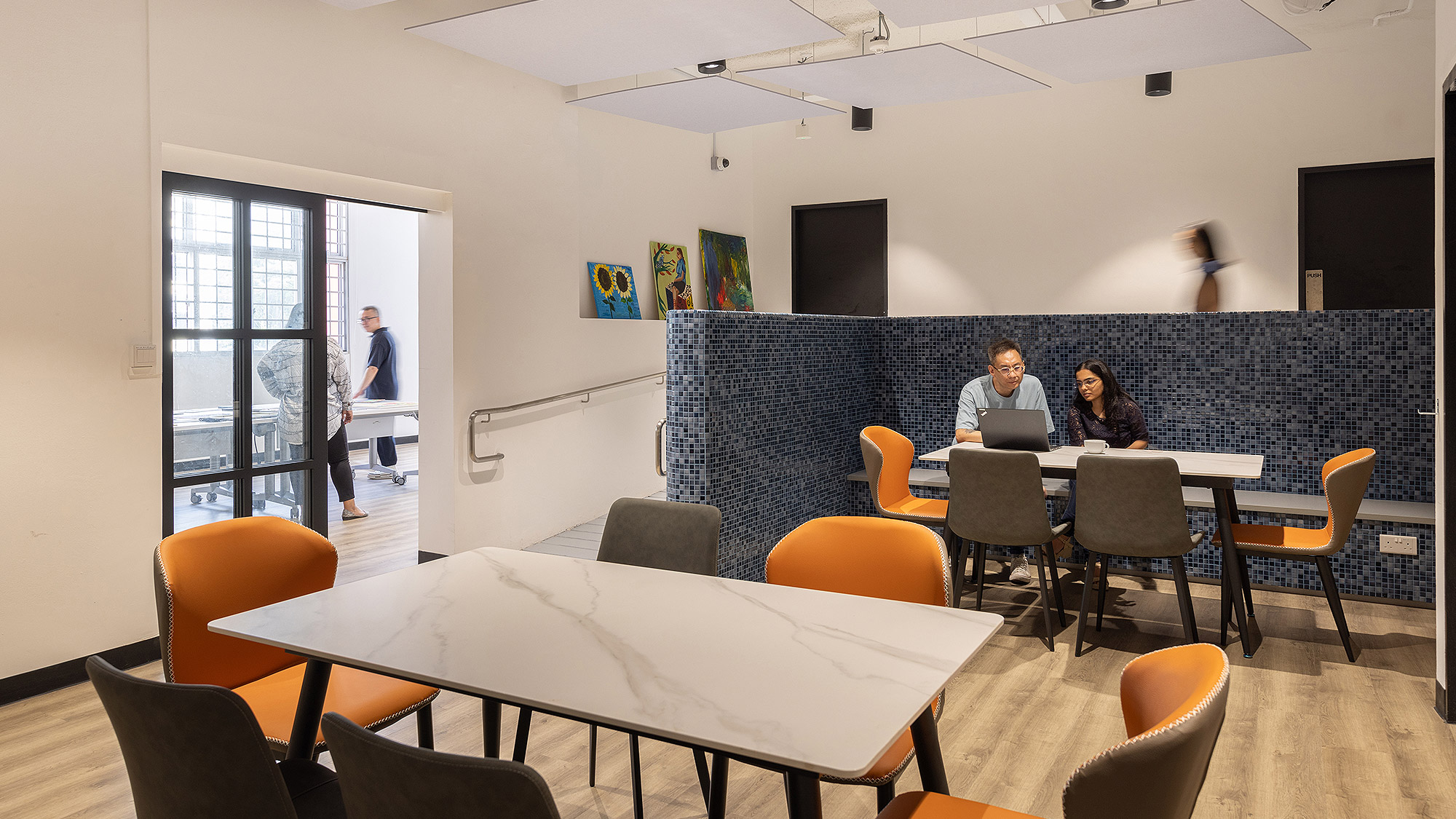 A man and woman sitting at a table in a room with chairs.