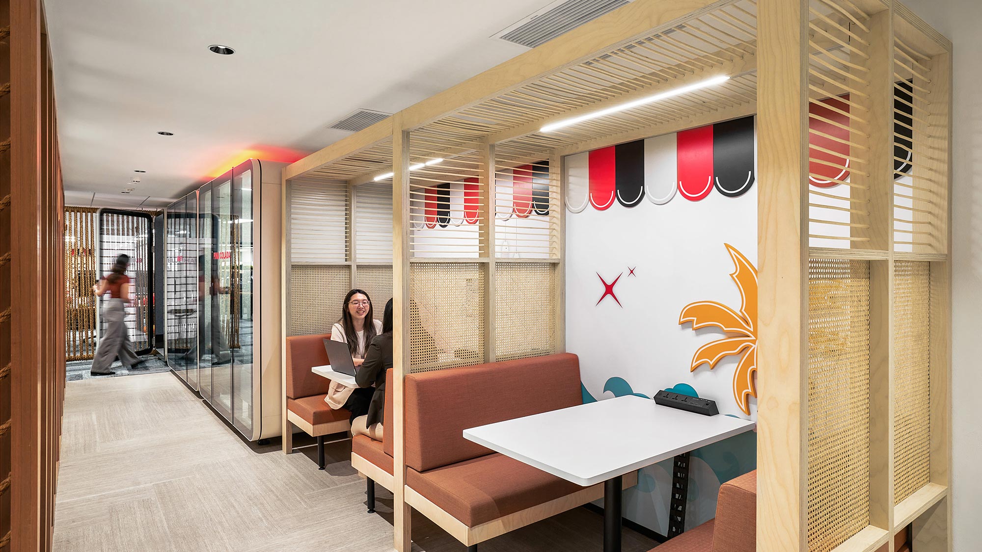 A person sitting on a bench in a room with a table and chairs.