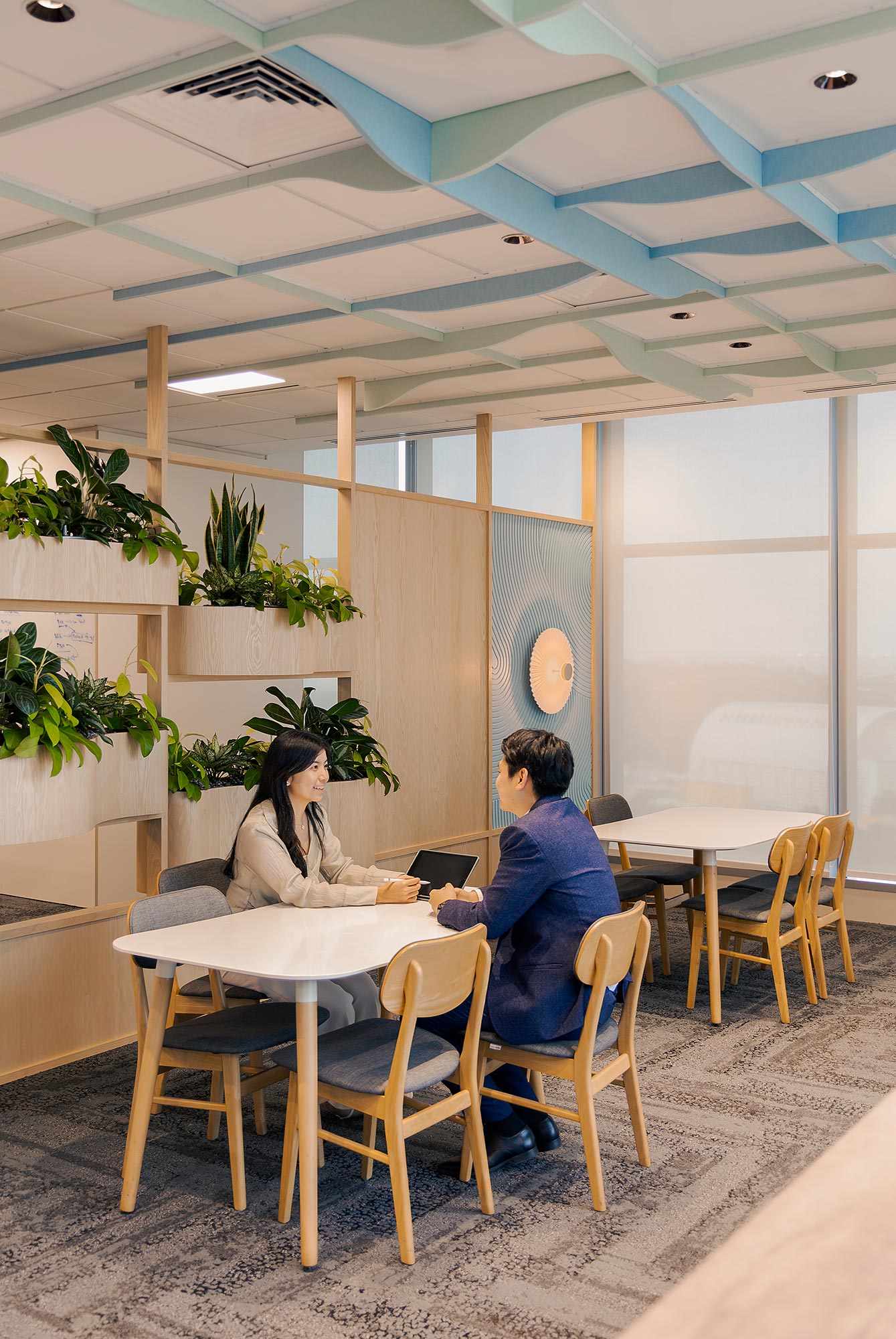 A man and woman sitting at a table in a room with a plant.