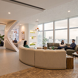 A group of people sitting on a couch in a room with windows.