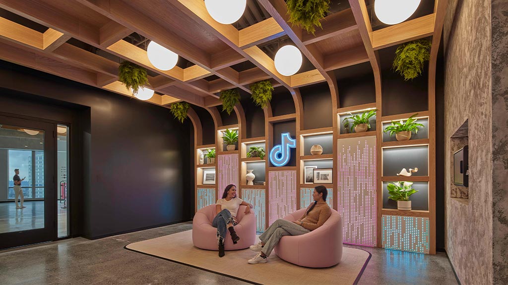 A couple of women sitting on a couch in a room with a wood ceiling and a wood ceiling.