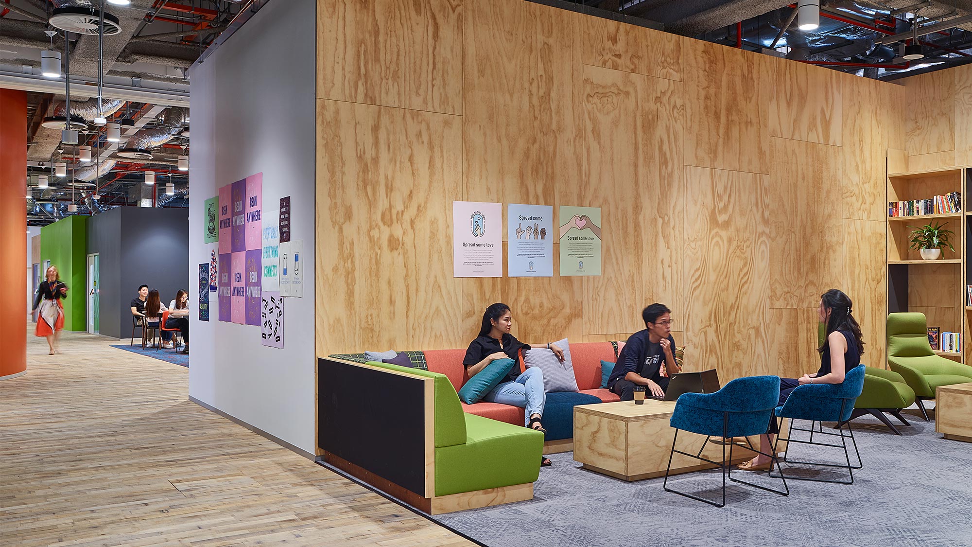 A group of people sitting on a couch in a room with a wood wall.