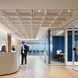 A person standing in a room with glass doors and people sitting at tables.