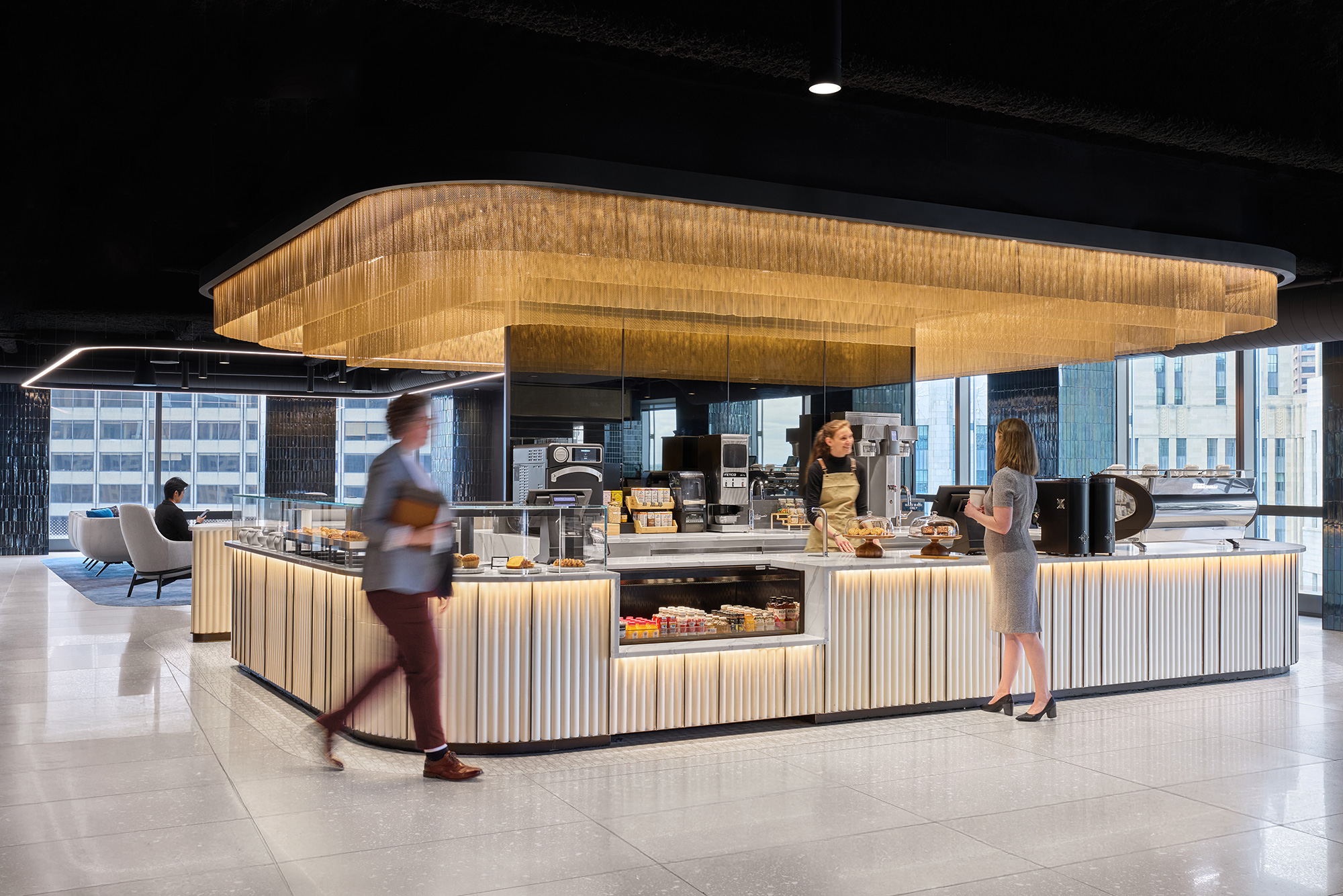 A group of people standing in a room with a counter and chairs.