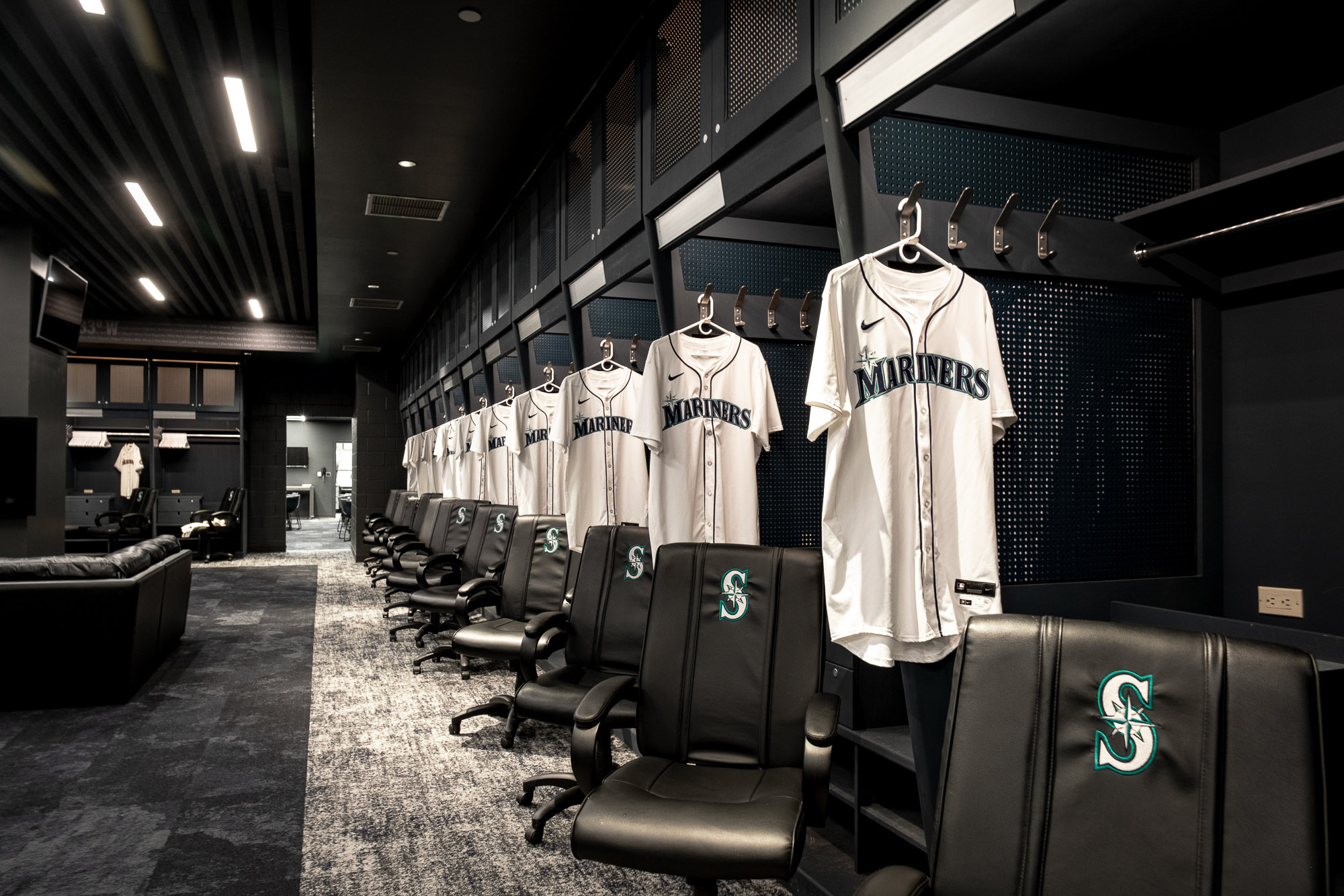 A room with a row of sports jerseys and chairs.