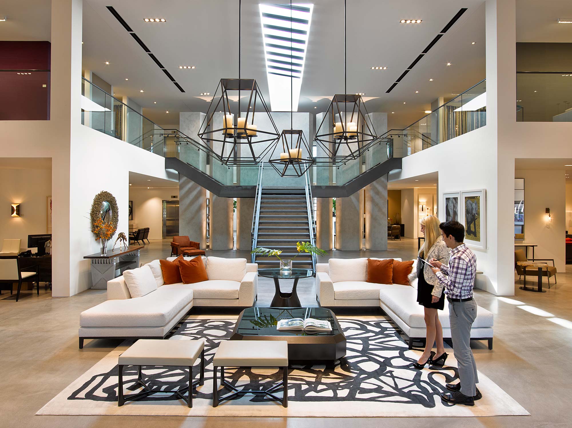 A couple of people in a large room with a large staircase.