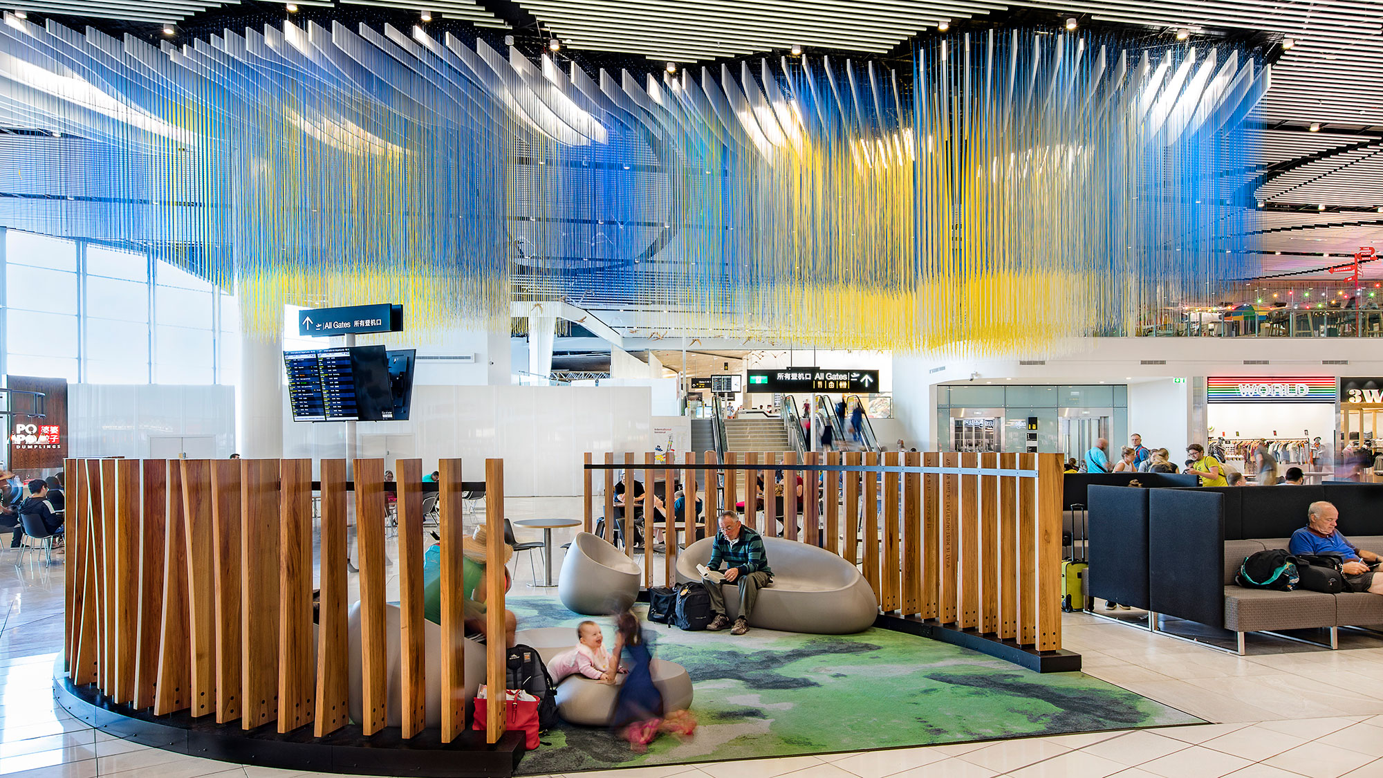 A group of people sitting on a couch in a large room with a large blue and yellow ceiling.