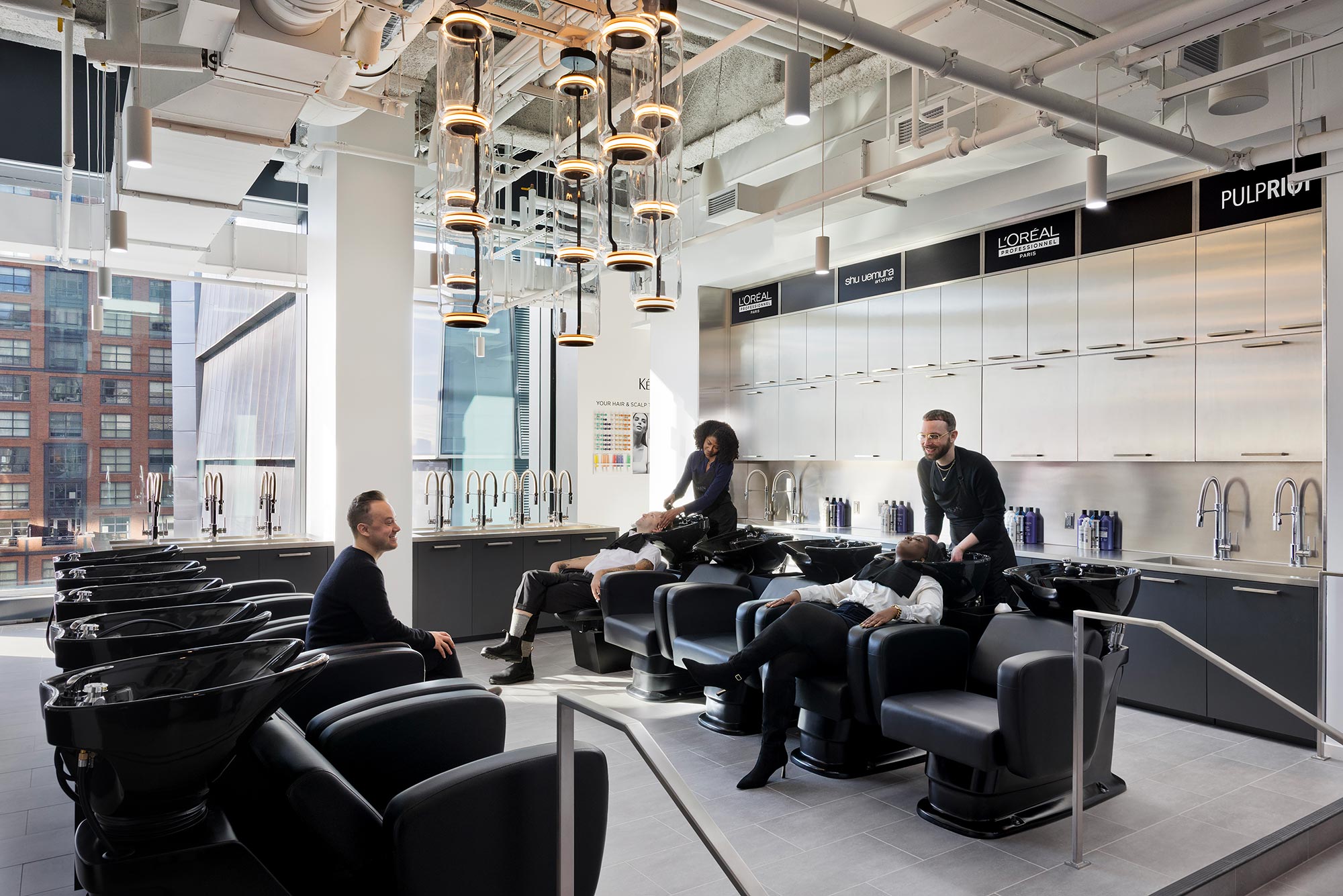 A group of people sitting around a table in a room with a large glass wall and a large.