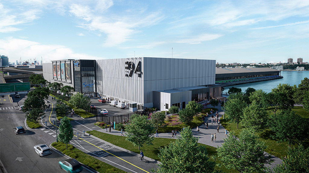 A large building with a parking lot and a body of water in the background.