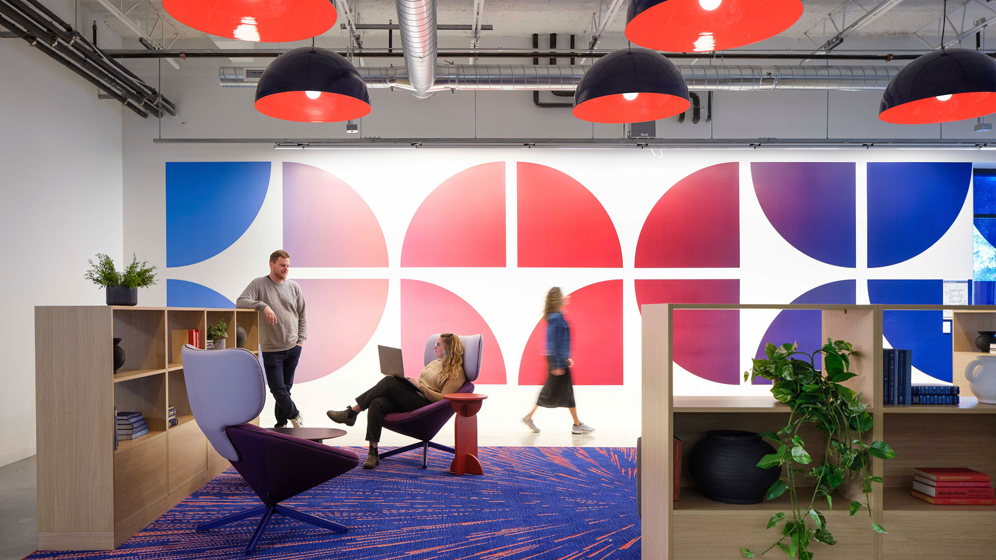 A group of people in a room with a stage and a large screen.