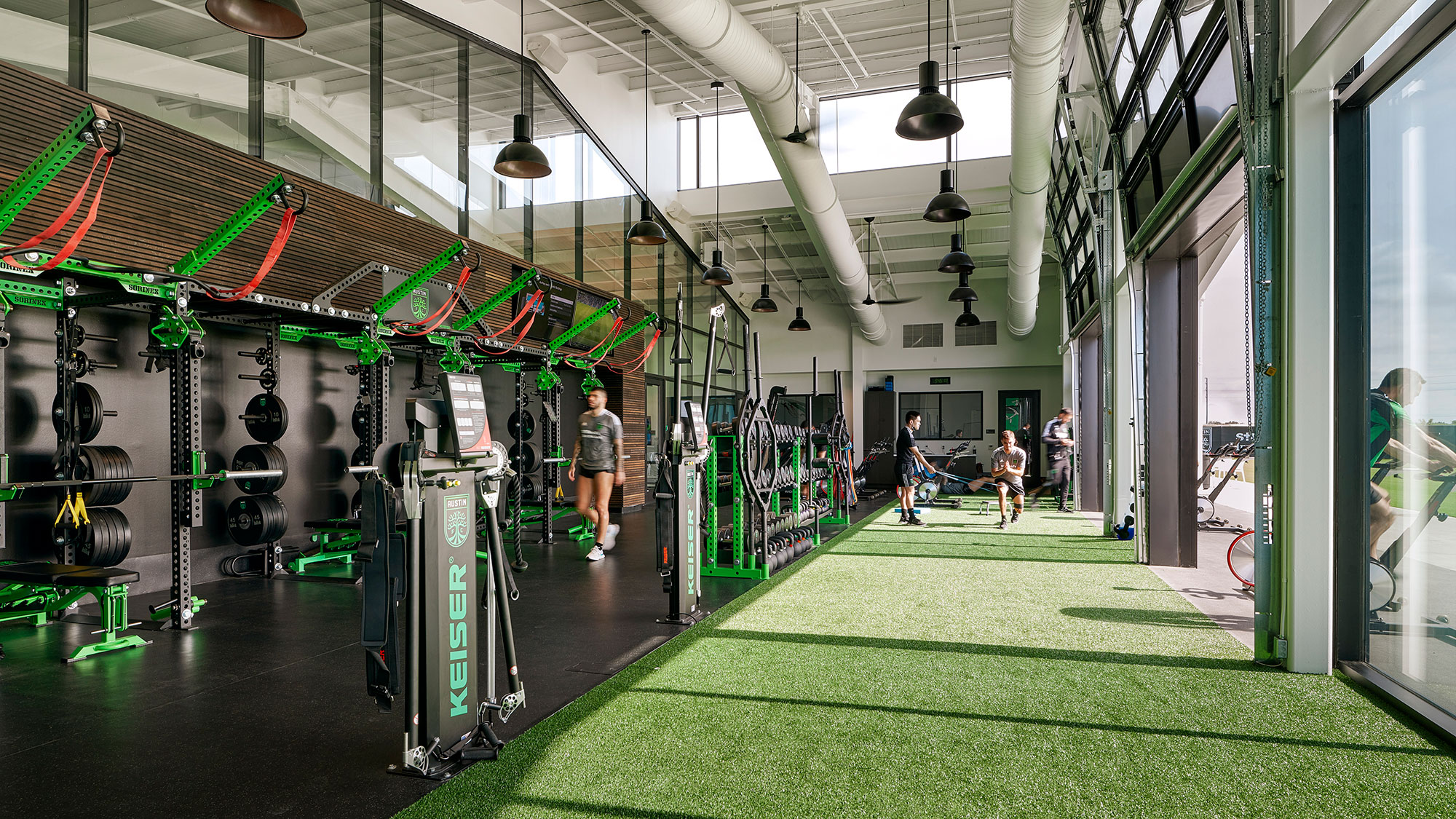 A room with a few people and a large display of electronic devices.