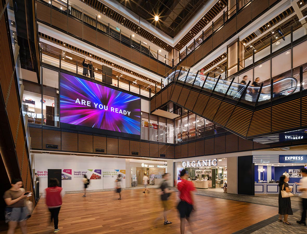 A group of people in a large room with a large screen.