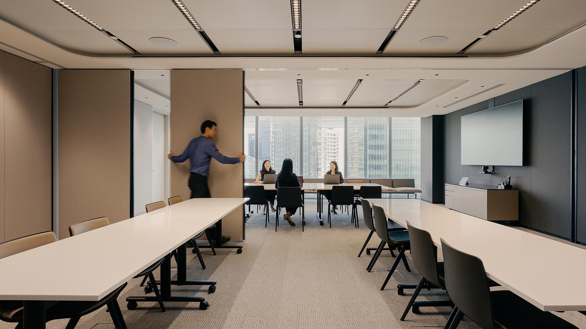 A person standing in a room with people sitting at tables.