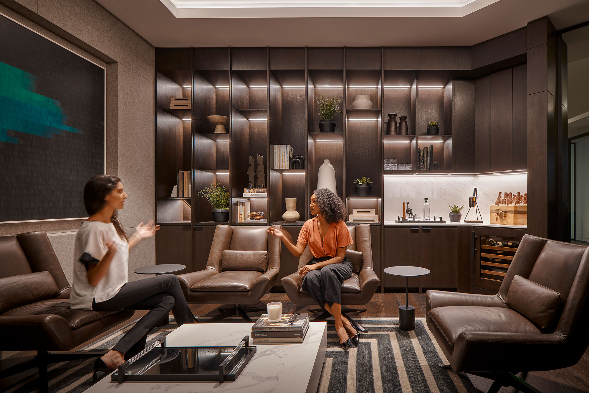 A couple of people sitting on a couch in a room with a large screen.