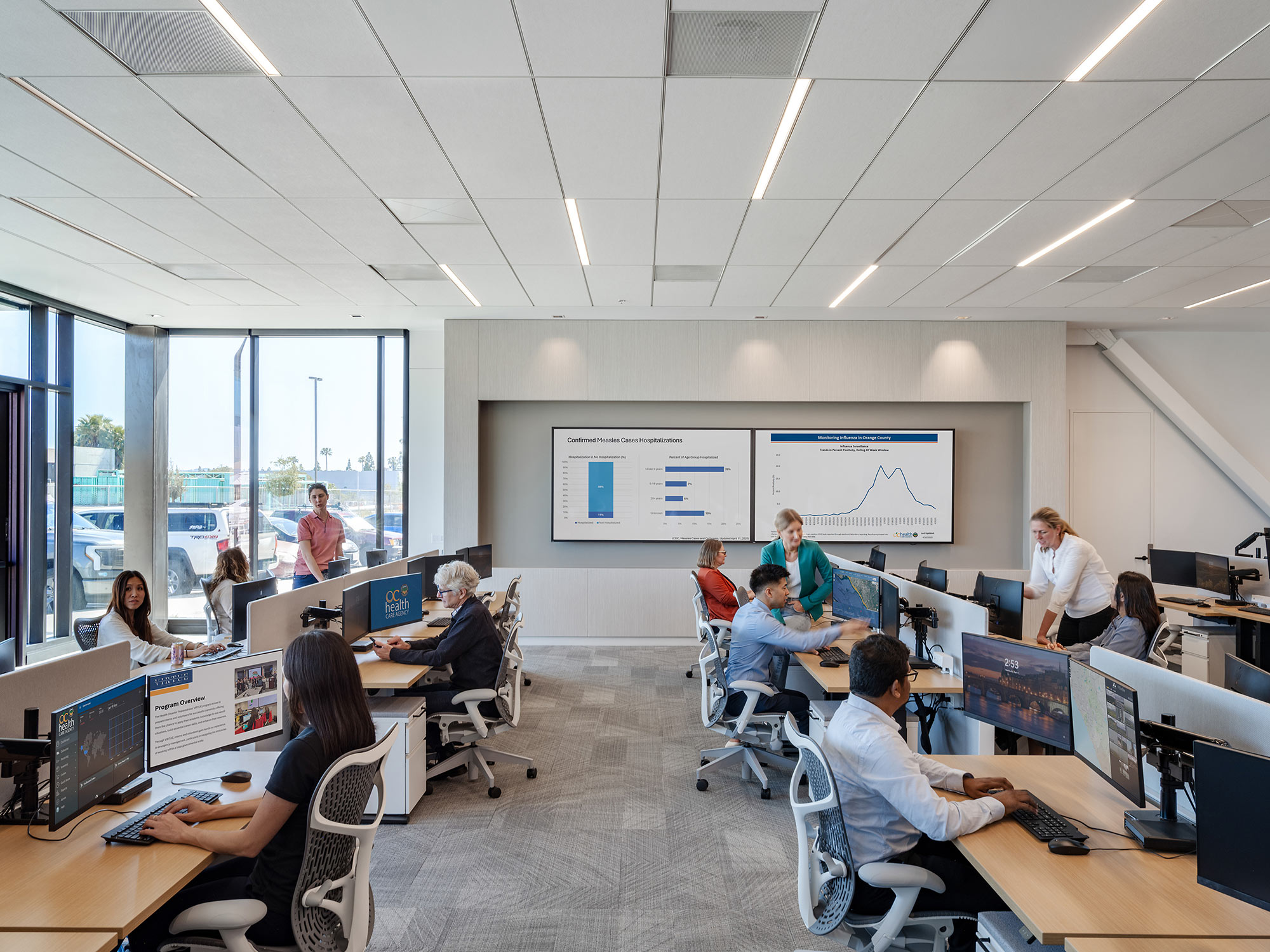 A group of people in a room with computers and a large screen.