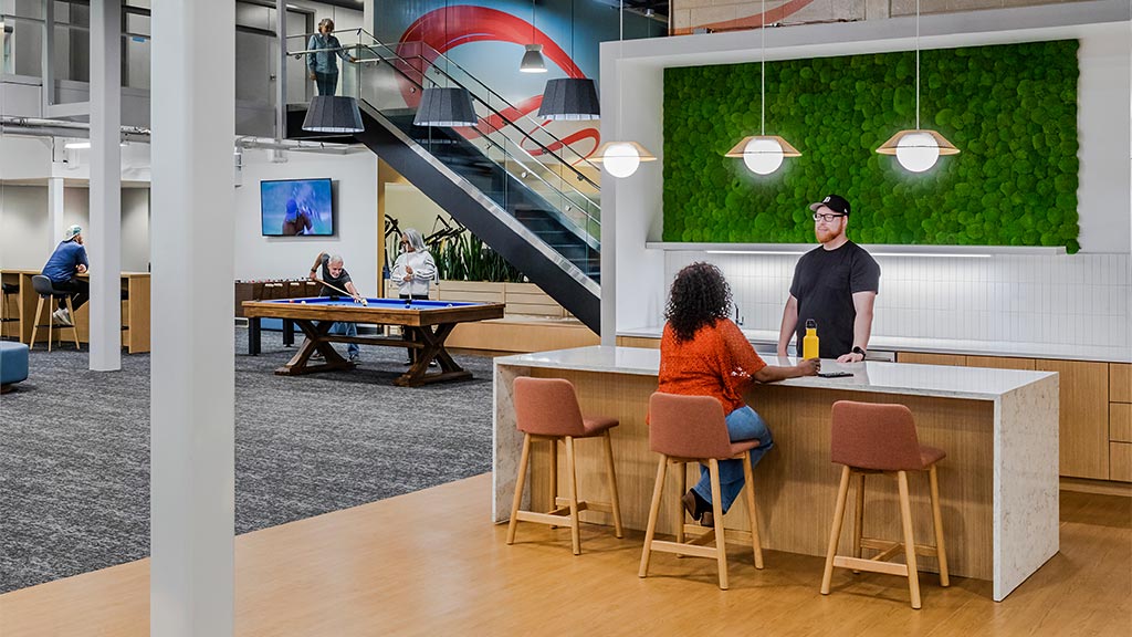 A group of people sitting at a table in a room with a large screen.