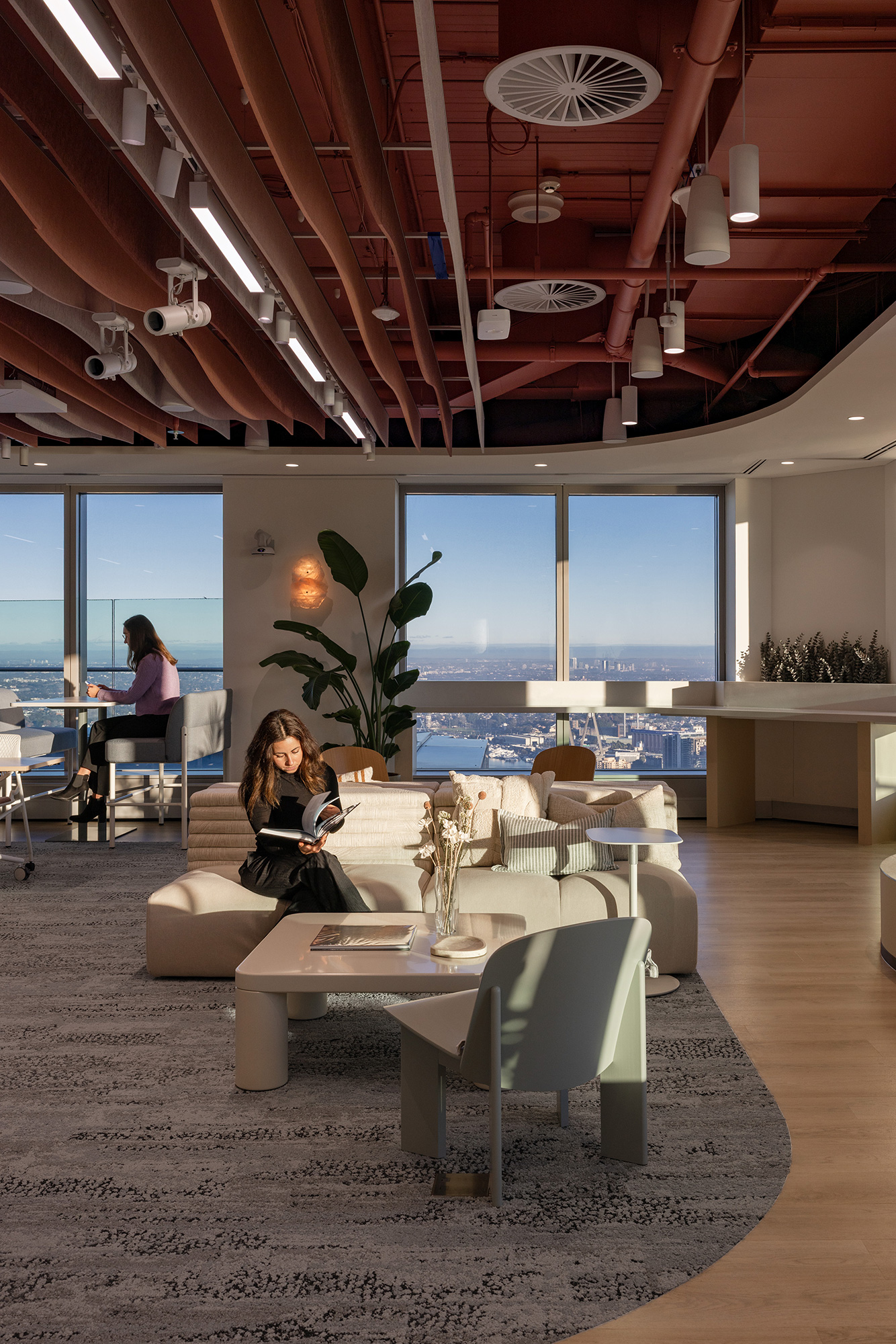 A couple of women sitting at a table in a room with a large window.