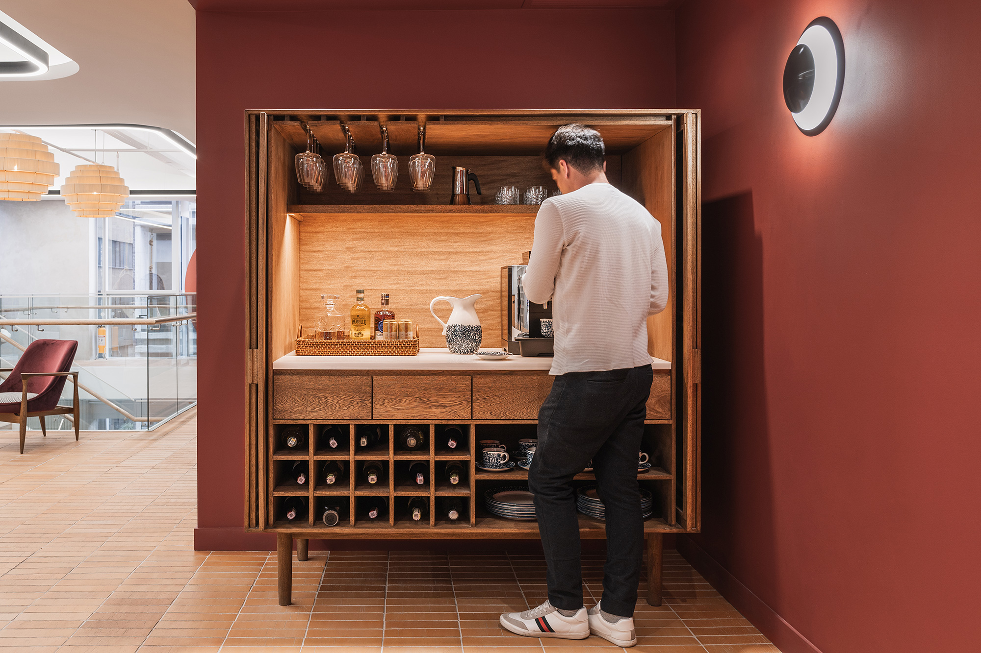 A man standing in front of a cabinet with wine bottles.