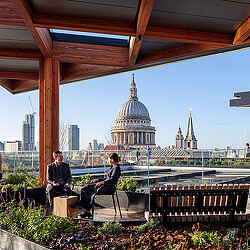 A couple sitting on a bench in front of a large building.