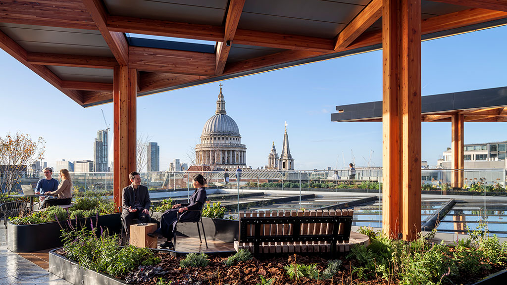 A group of people sitting on a bench in front of a city.