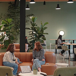 A couple of women sitting on a couch in a room with a man standing and a woman sitting.
