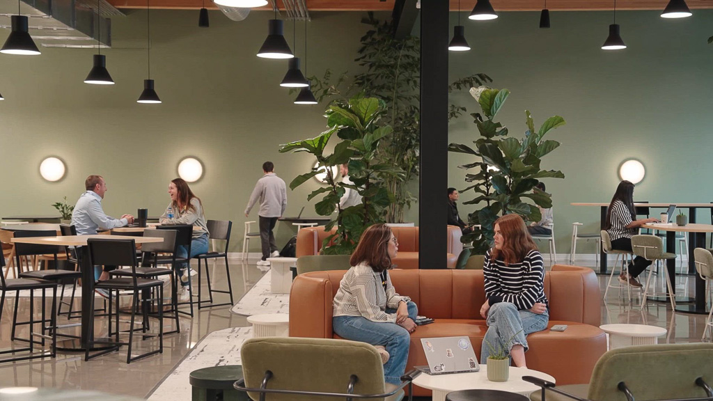 A group of people sitting on a couch in a room with tables and chairs.
