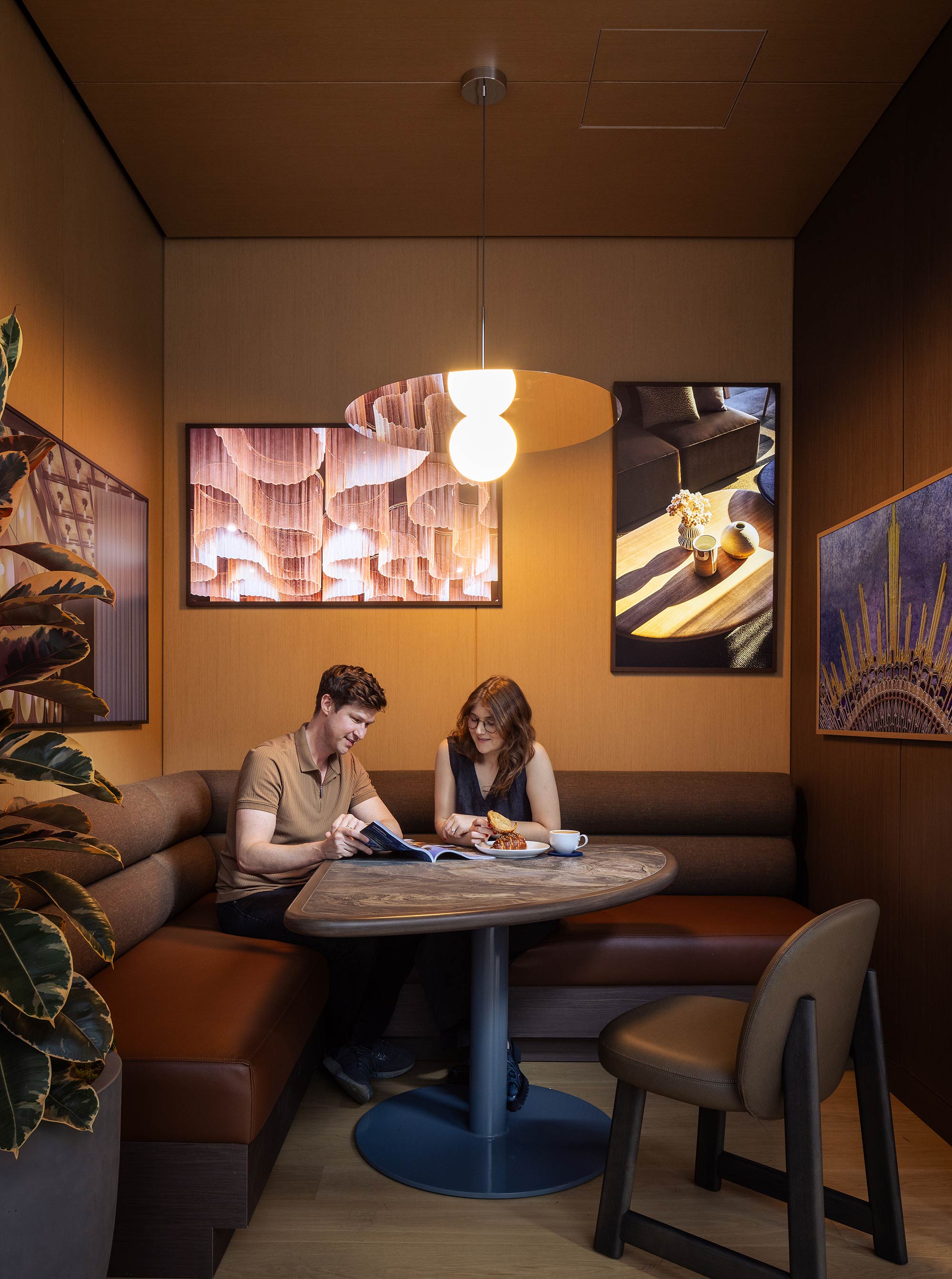 A man and a woman sitting at a table in a room with art on the wall.