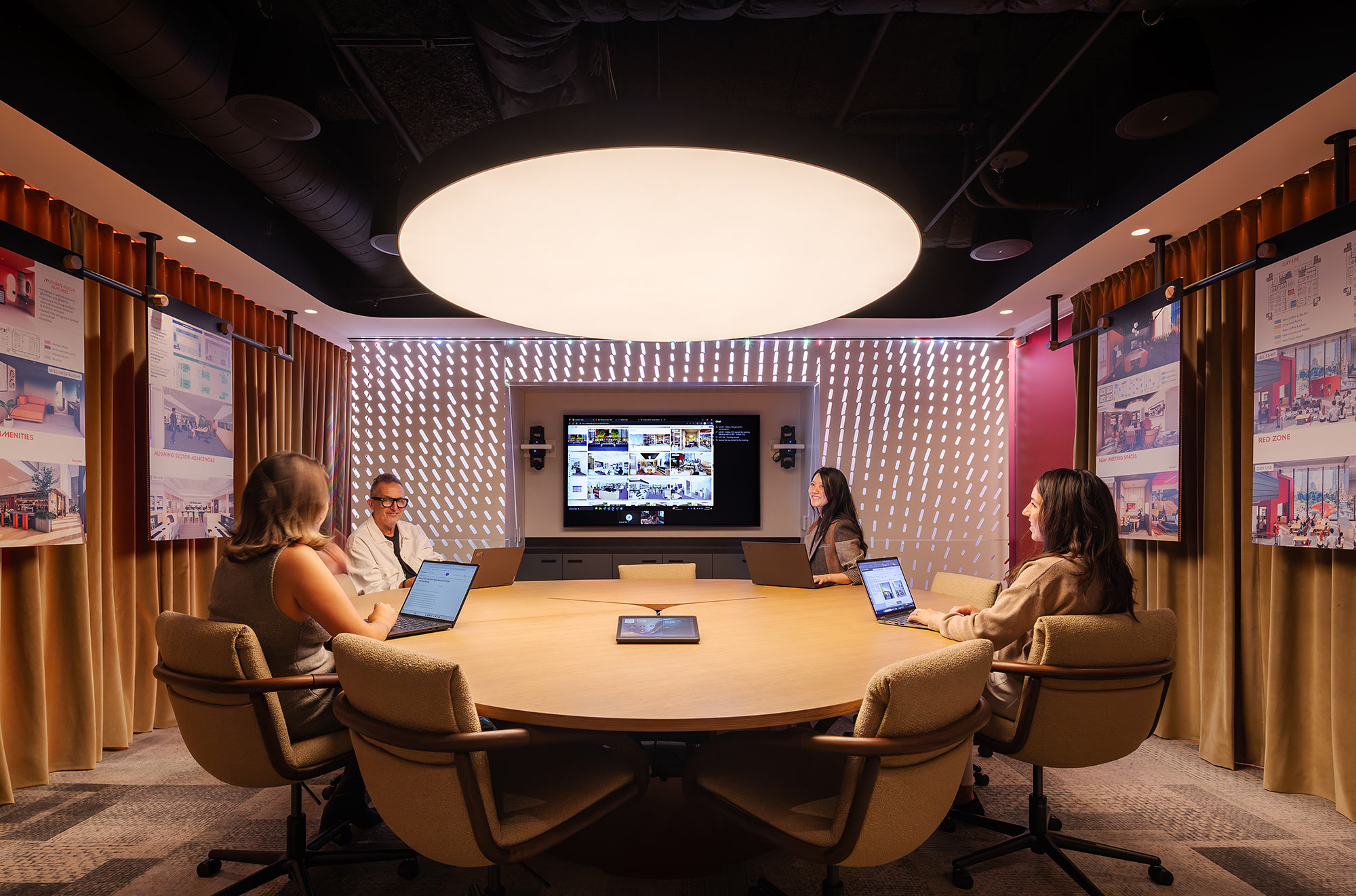 A group of people sitting at a table with laptops.