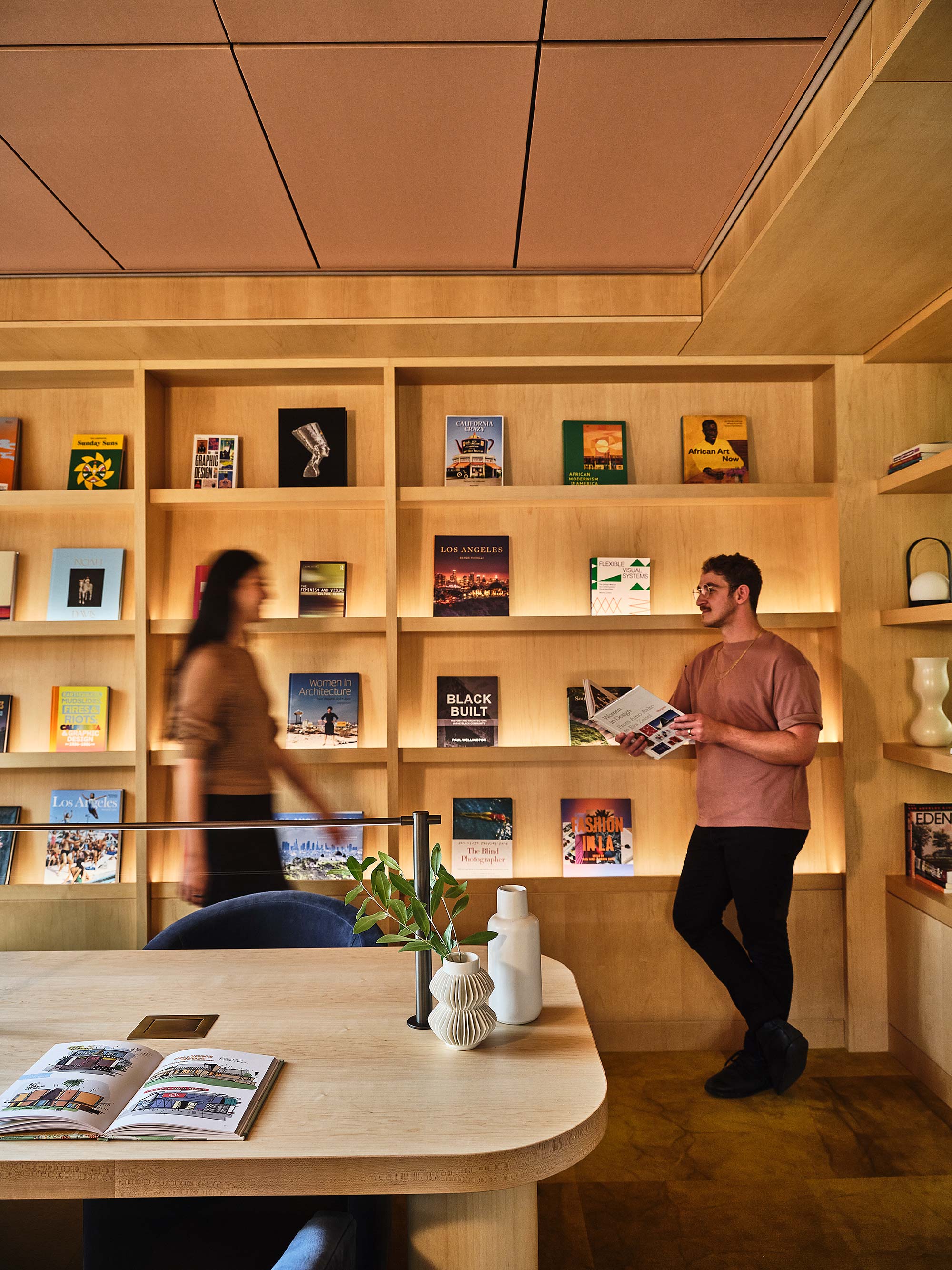 A man and woman standing in front of a shelf with books.