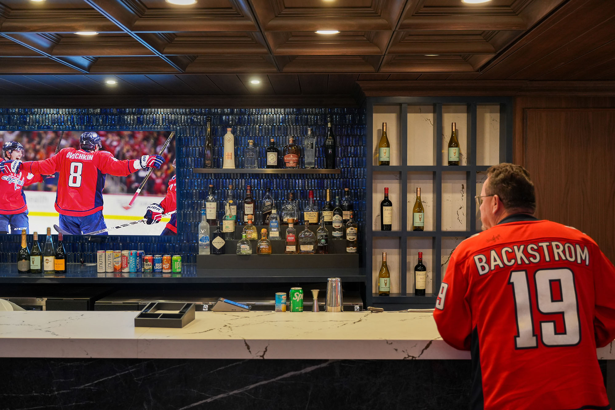 A person standing in front of a bar with a large display of liquor.