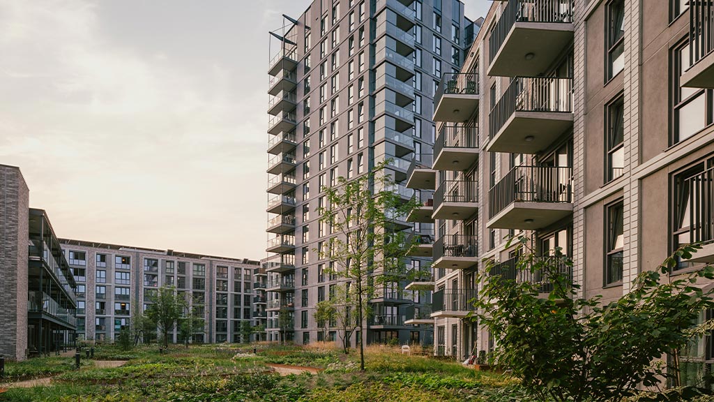 A group of buildings with balconies and trees in front.