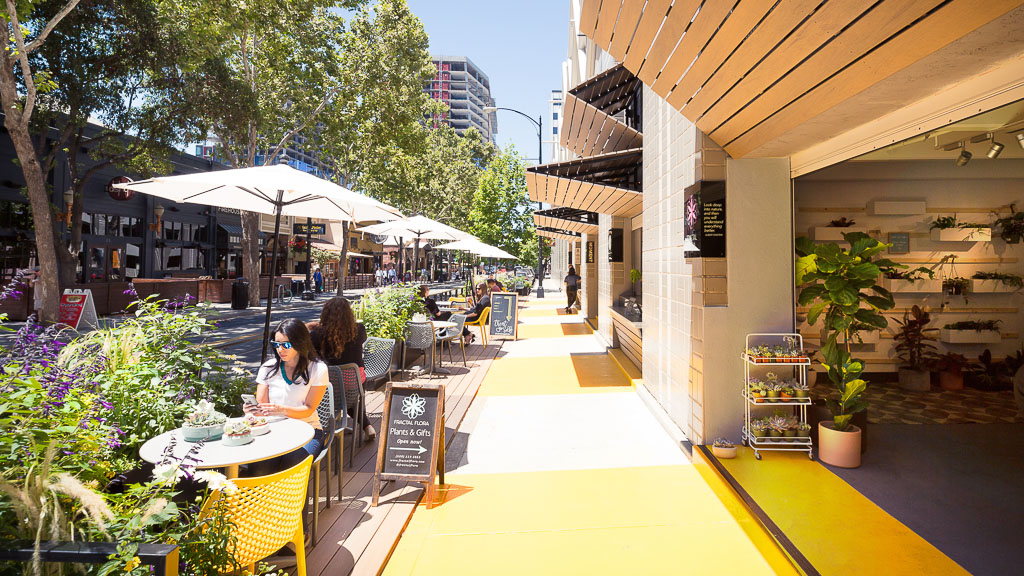 A group of people sitting at tables outside.