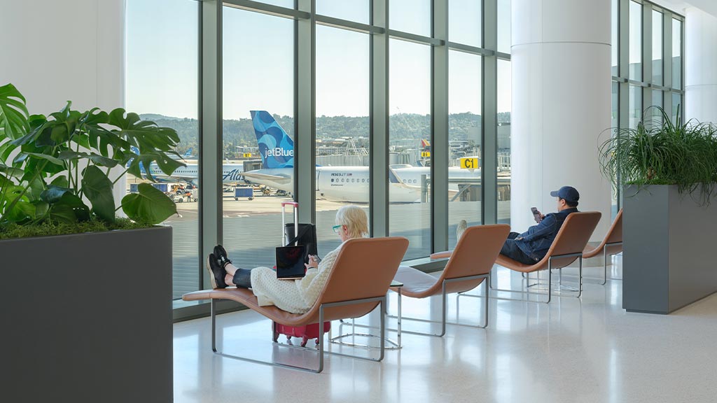 A man and a woman sitting in chairs in a room with large windows.