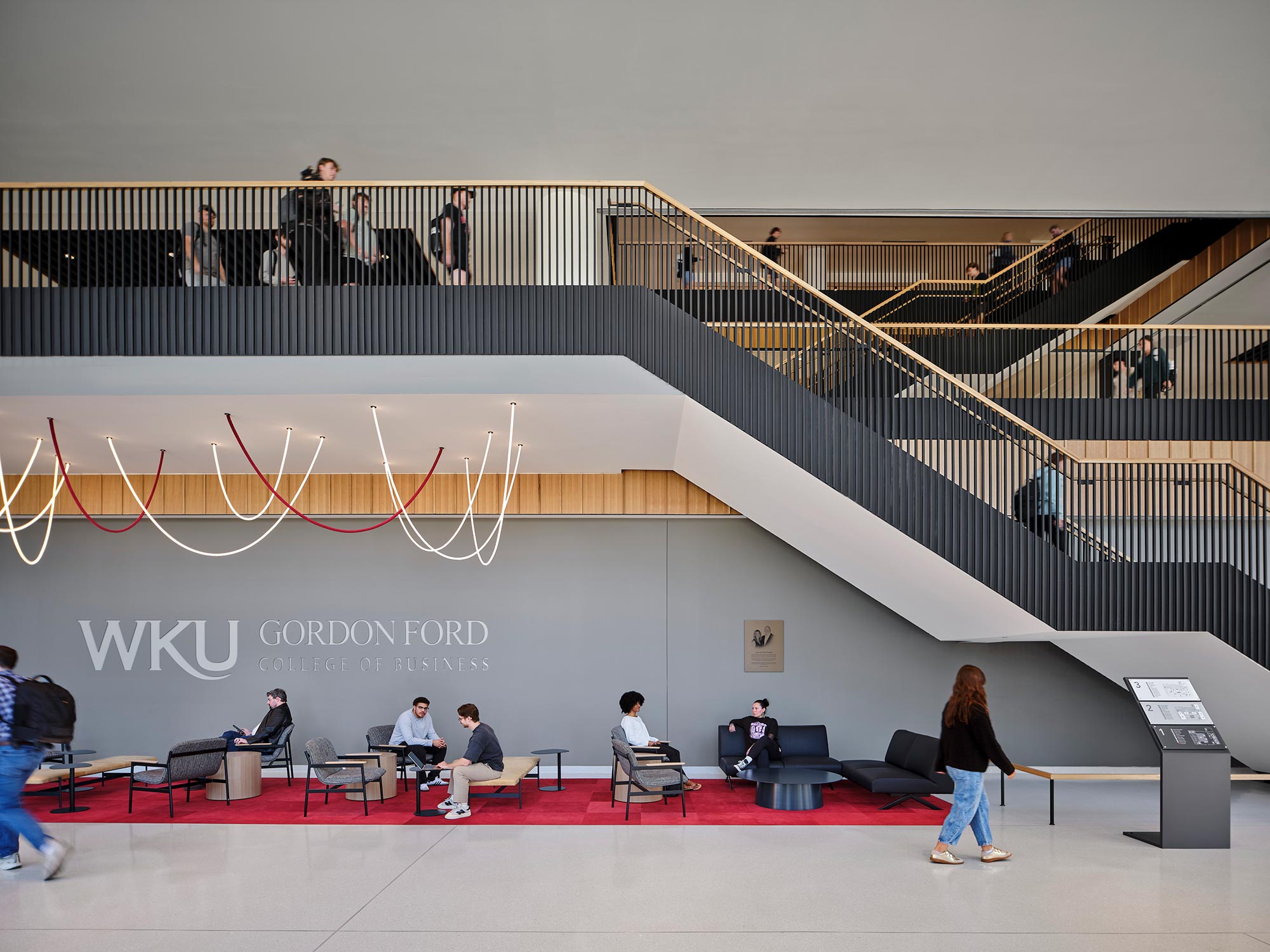 A group of people sitting on chairs in a room with a large banner.