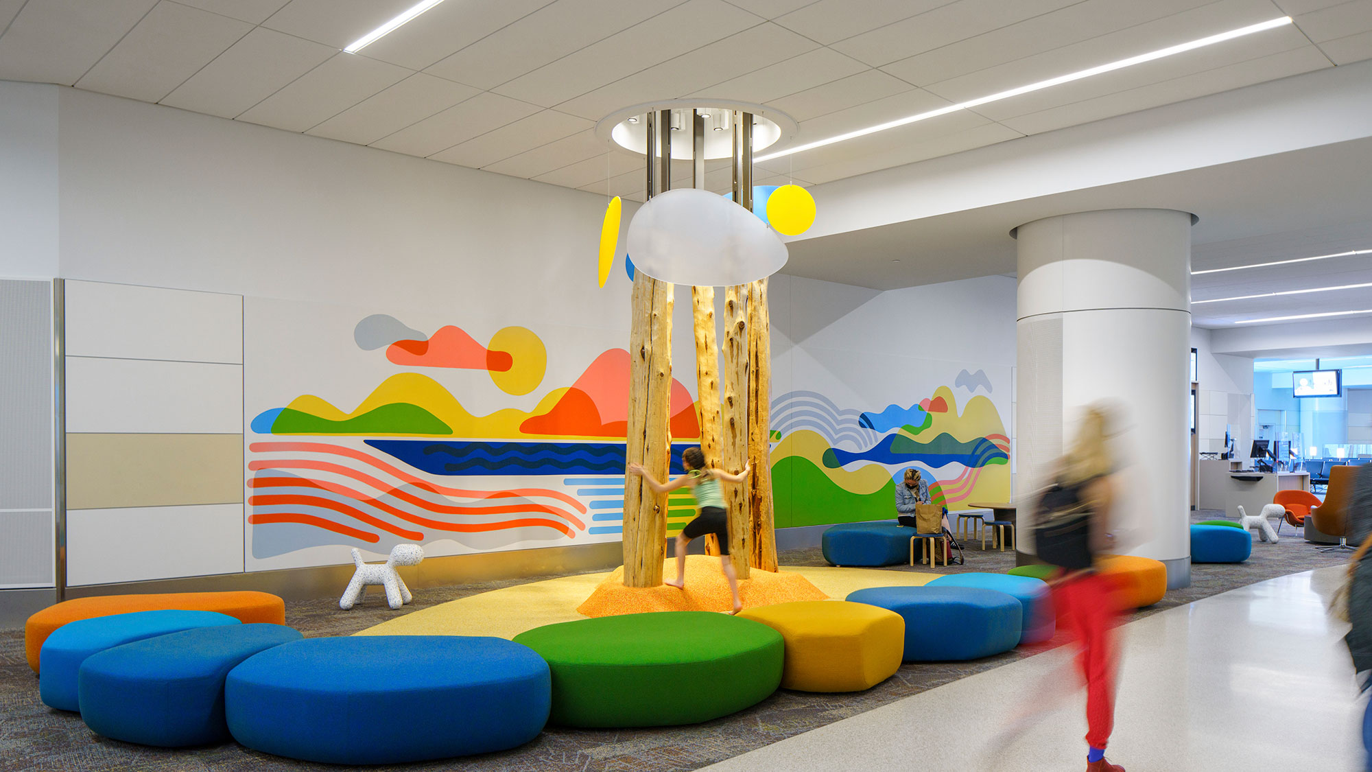 A group of people playing in a room with colorful cushions.