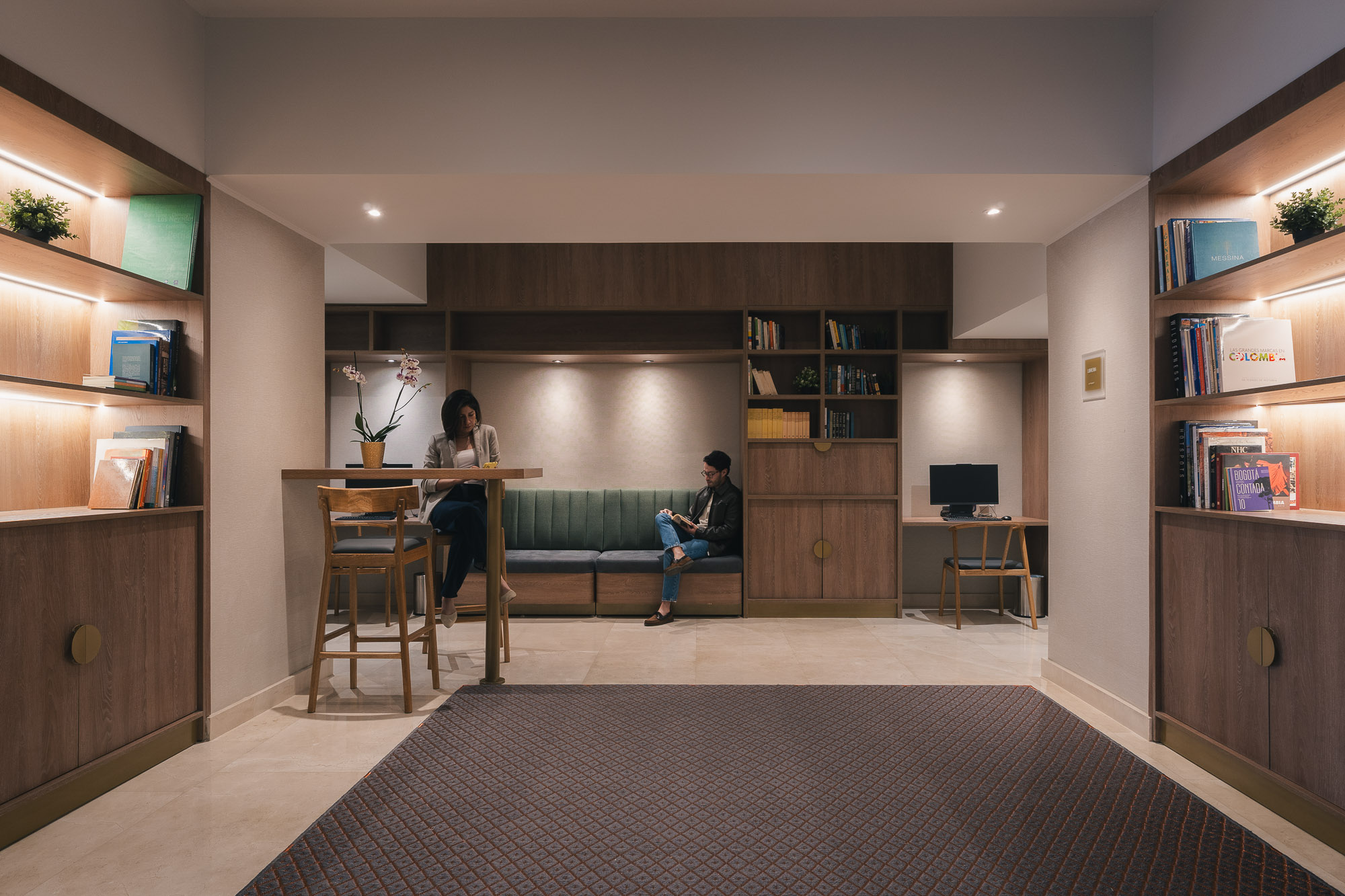 A man and woman sitting at a table in a room with shelves.