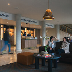 A couple of women sitting on couches in a lobby.