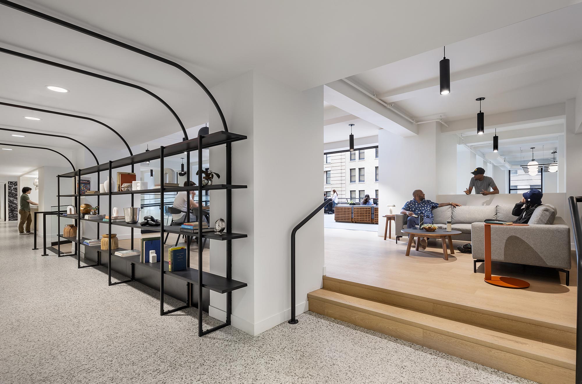 A room with a glass wall and a couple of people sitting on couches.