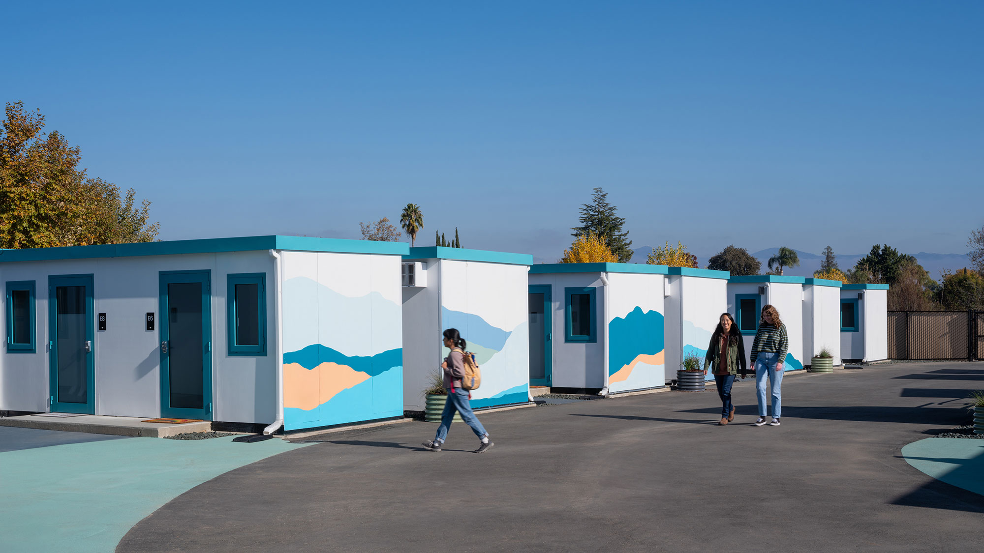 A group of people walking by a row of blue buildings.