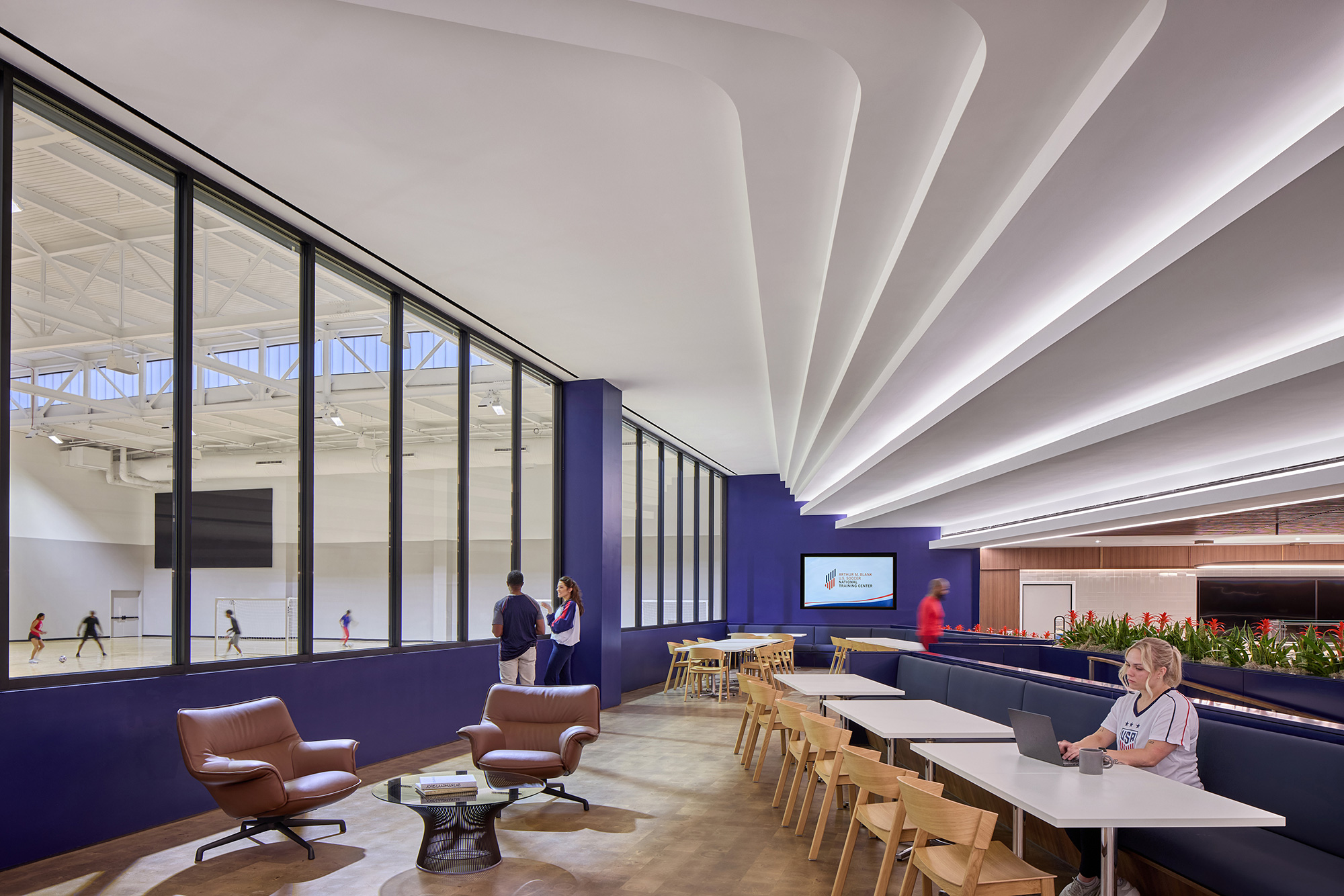 A room with tables and chairs and people in it.