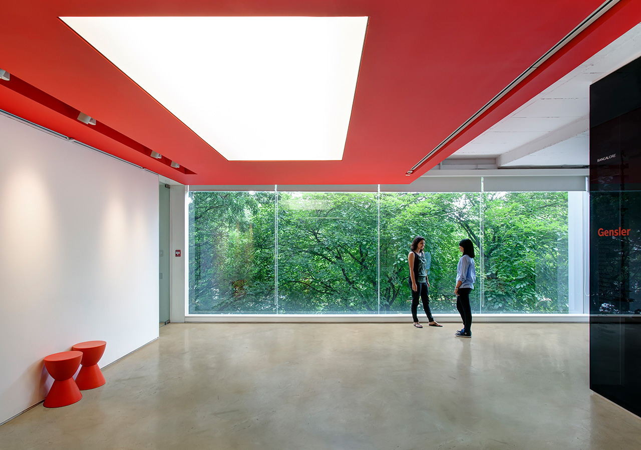 A couple of people walking in a room with red walls and windows.